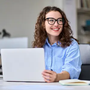 Woman in glasses using a laptop at a desk.