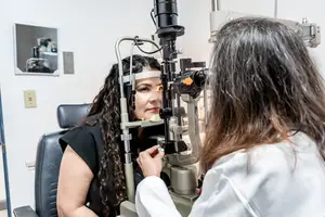 A woman is having her eyes examined by a doctor at an eye clinic