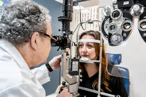 a man checking a woman's eyes with a slit lamp