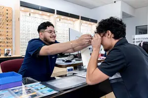 Two men at a glasses shop where one is having his eye checked