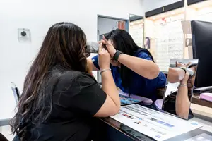An optometrist is testing the vision of a customer in an optometrist shop