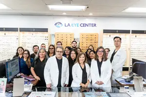 A group of people in white coats and glasses are posing for a photo in an eye center.