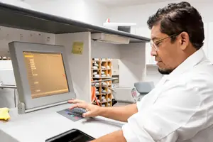 A man is typing on a computer with a monitor in a laboratory setting.