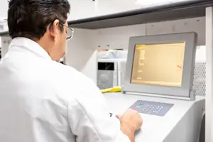 A man in a white lab coat is using a machine in a lab