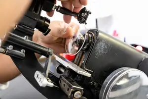 A person's hand is adjusting a slide under a microscope.