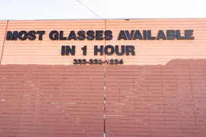 The side of a building with a sign that reads 'Most Glasses Available in 1 Hour'.