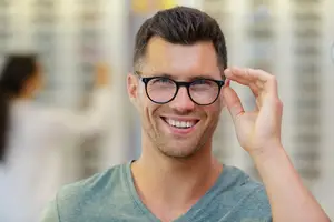 A man adjusting his glasses in a store