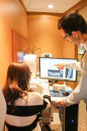 A man and a woman are looking at a computer screen that displays an image