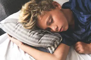 A boy sleeping on a pillow in bed