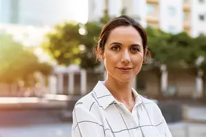 portrait of woman in white shirt smiling in front of building