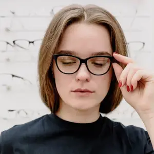 Woman adjusting glasses in front of a display of glasses