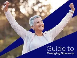 A senior woman with short gray hair is raising her hands and smiling, possibly at a healthcare event or seminar, with a blue background that reads 'Guide to Managing Glaucoma'.