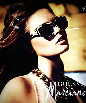A woman wearing sunglasses and a necklace with the words Guess Marciano on her