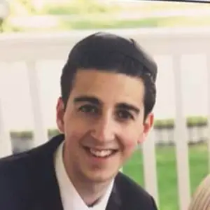 Image of a man smiling with short hair and wearing a black suit