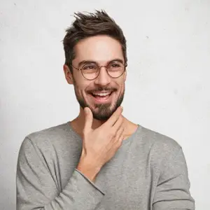 A man with a beard and glasses is smiling and posing for a photo.