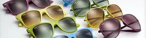A collection of colorful sunglasses with various lens colors and frame shapes are displayed on a white surface