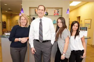 Four people standing in a room with yellow walls and smiling at the camera