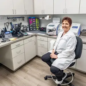 A woman in a white lab coat sitting in a chair in a lab