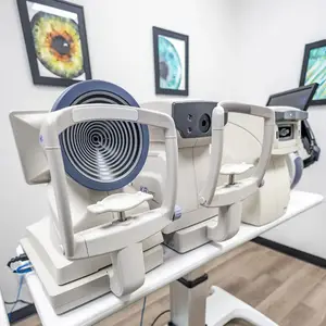 Three medical devices, including one with a spiral lens, are placed on a white table in a medical room.