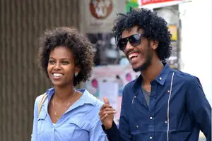 A man and a woman smiling at each other while walking on the street