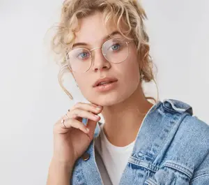 young woman in glasses and denim jacket posing for a picture