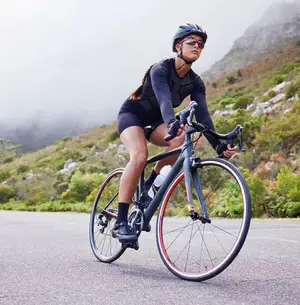 A woman is riding a bicycle on a mountain road