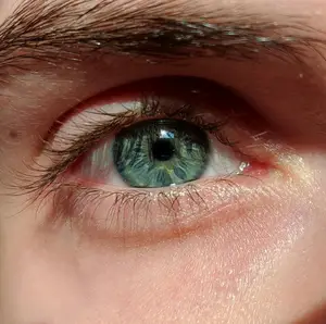 Close-up of a person's eye with green iris and visible eyelashes.