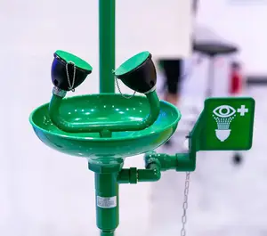 A green eye wash station with two spouts and a green label with a plus sign and eye symbol