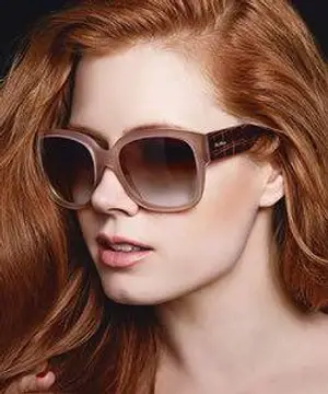 Red-haired woman wearing sunglasses in a studio photo