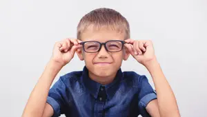 A young boy wearing glasses and smiling for a photo