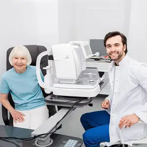 An older woman sits in a chair while a man in a white coat sits next to a machine in a medical office