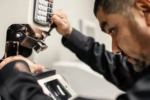 A man is adjusting a machine with a remote control in his hands.