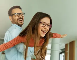A man and her daughter are laughing together at Lithonia Family Eyecare in Stonecrest, GA.