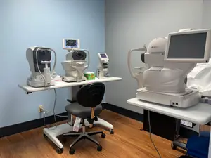 Medical diagnostic equipment in an empty examination room with blue walls and wood floors.