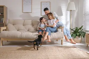 A family with two children and a dog is sitting on a couch in a living room.