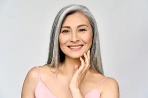 A woman with gray hair is smiling and posing for a photo
