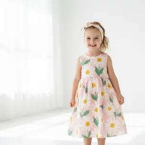 A little girl in a pink dress with white flowers and green leaves