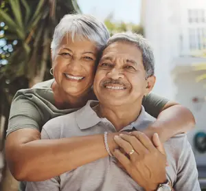 An older couple embracing each other in front of a building