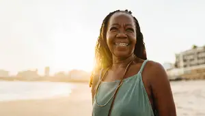 A woman standing on a beach smiling at the sun.