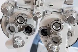 Close up of a pair of ophthalmoscopes with a white background and silver lenses.