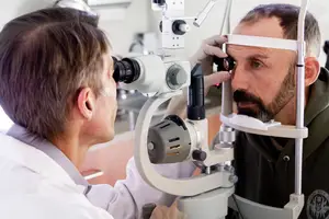 A doctor examining a patient's eyes using an ophthalmoscope.