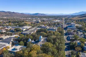 Aerial view of a city with many buildings, trees, and mountains in the distance