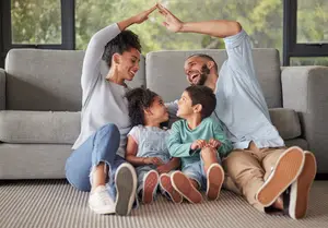 A family sitting on a couch in their living room with one child sitting on the floor