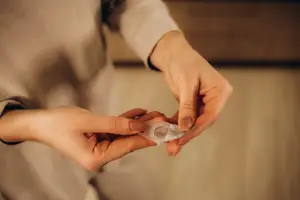 A woman is holding a small transparent plastic container in her hands
