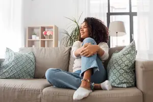 Woman sitting on a couch and smiling while looking to the side