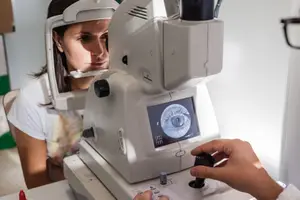 A woman having her eye examined by an optometrist using a retinal imaging machine