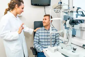 A woman doctor is helping a man check his eyes in a clinic.