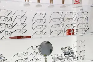 A glass shelf displaying a variety of eyeglasses and a mirror with a red box reading Morel.