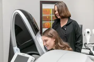 A woman is having her eyes checked by an eye doctor in a medical room.