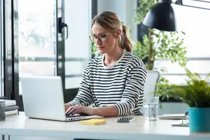 Woman working on a laptop at a desk in an office
